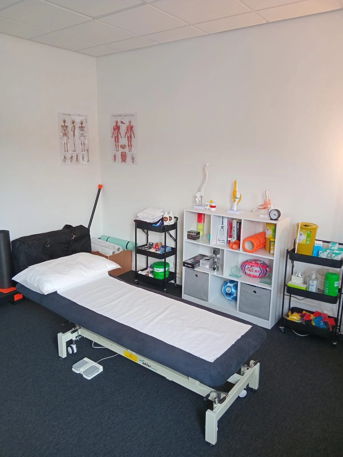 The physiotherapy treatment room at Joint Venture Physiotherapy in Bolton, with treatment plinth, anatomy charts and rehabilitation equipment