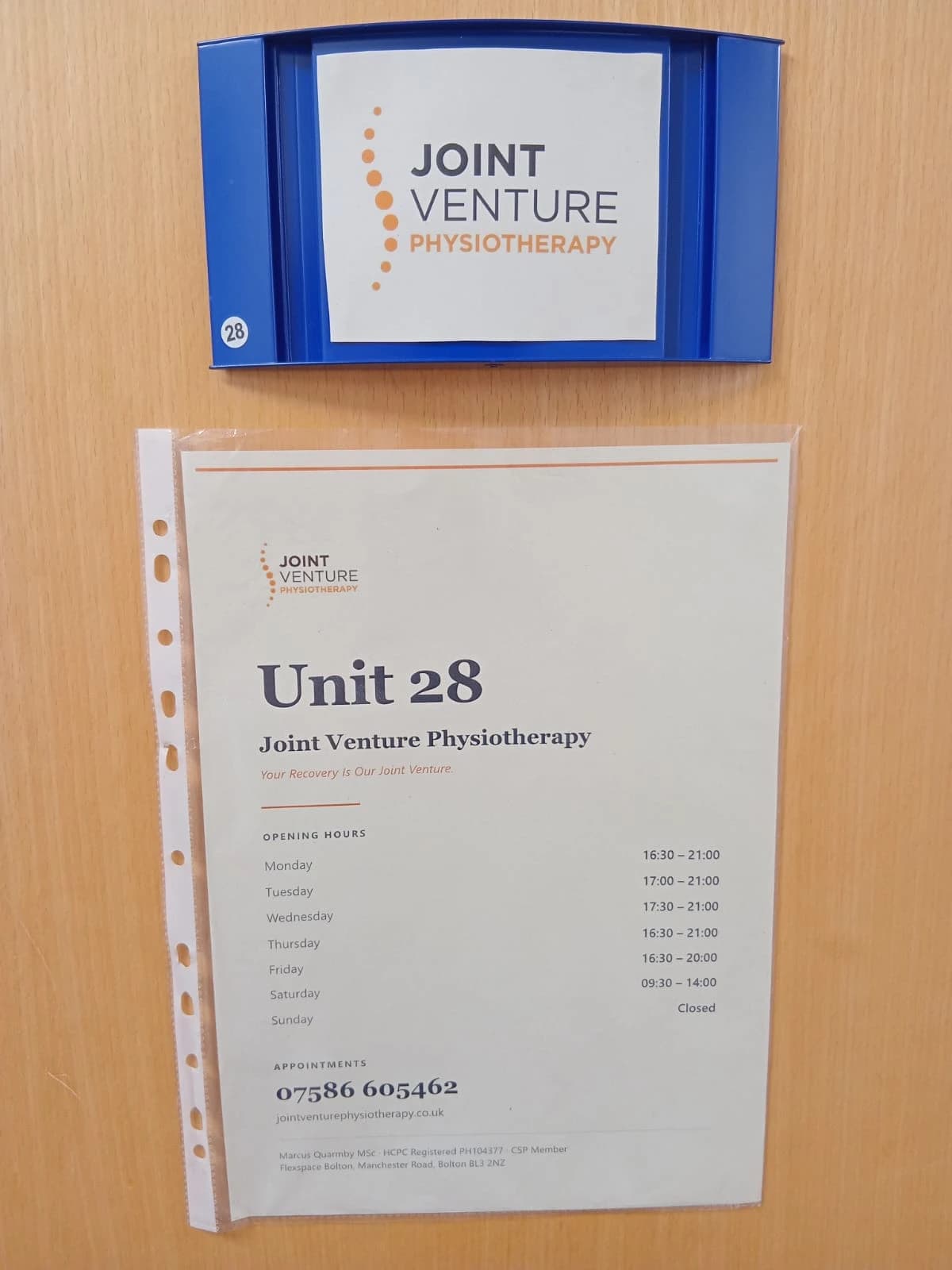 The Joint Venture Physiotherapy sign on the door of Unit 28 at Flexspace Bolton, showing opening hours and appointment phone number